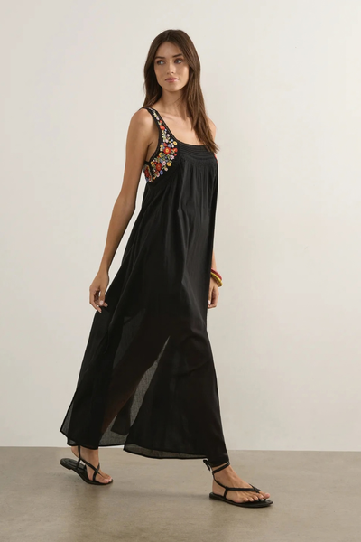 Studio side-profile shot of a model walking in the relaxed-fit black maxi dress, showing the side seam split and flowy silhouette.