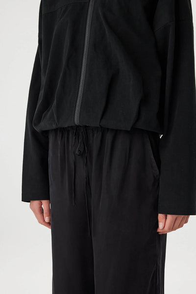 A view of the waist focusing on the elasticated hem, which creates a classic bomber "bubble" shape while maintaining a minimalist profile.