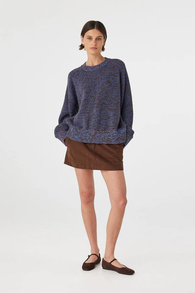 A dynamic, slightly angled full-body studio image showcasing the natural structure of the 100% cotton knit during movement.