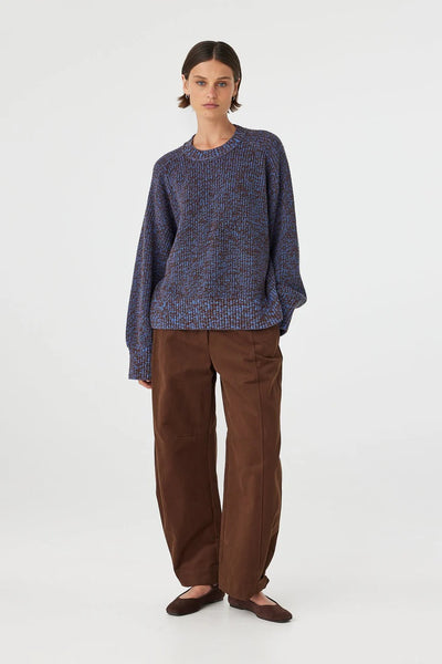 A dynamic, slightly angled full-body studio image showcasing the natural structure of the 100% cotton knit during movement.