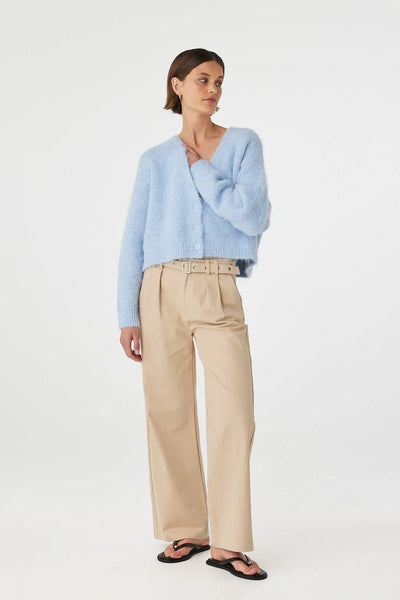 Front three-quarter view of a model in the Arcaa Movement Liora Fluffy Cardigan. The light pastel blue cropped knitwear piece is shown buttoned up, emphasizing its soft tactile hand-feel and easy, relaxed fit architecture.