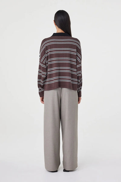 A full-length rear studio shot showcasing the back design of the Rayne Knit Jersey. This angle highlights the dropped shoulders, the intentional slouch of the wide body, and the continuous espresso, black, and cream horizontal stripe pattern.