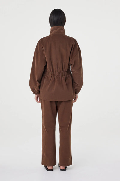 A full-length studio shot from behind, displaying the back design of the Amari Jacket. This angle emphasizes the soft structured feel of the cotton velvet fabric, the dropped shoulders, and the continuous gathered elastic waist point.