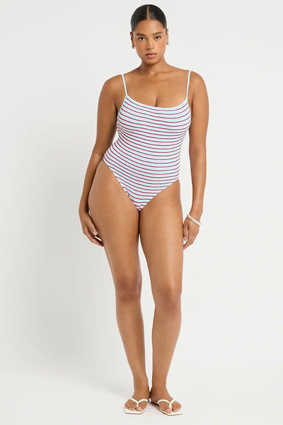 Studio front view of a curve model wearing a light blue and red micro-striped crinkle-fabric one-piece swimsuit with a square neckline and thin adjustable shoulder straps.