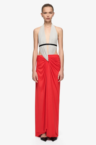 Full-length studio front view of a model wearing a multi-colored soft mesh maxi dress featuring a dove grey halter top, black underbust accent band, side waist cutouts, and a gathered flame red maxi skirt styled with black pointed pumps.