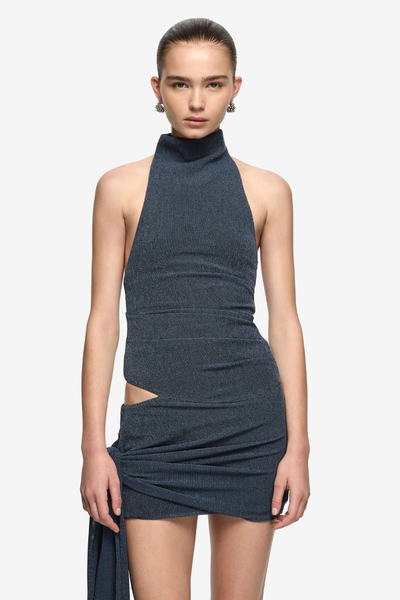Three-quarter studio front shot of a model wearing a denim marle stretch-knit mini dress with a high funnel neck, sleeveless cut, right waist cutout, and draped hip tie.