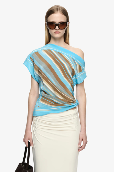 Full-body front studio view of a model wearing the Bec + Bridge Elaris Drape Top in Sandalwood Stripe with a cream maxi skirt, sunglasses, and a dark brown handbag.