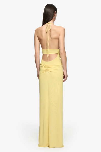 Full-length studio rear view of a model showing the open back cut-out, delicate neck halter ties, and ruched lower back detail of a citron yellow maxi dress.