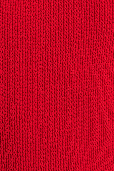 Extreme close-up shot of the bright red textured crinkle swimsuit fabric.