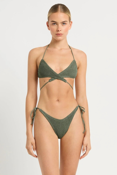 Studio front view of a model wearing the khaki green crinkle triangle bikini styled with cross-front waist ties.