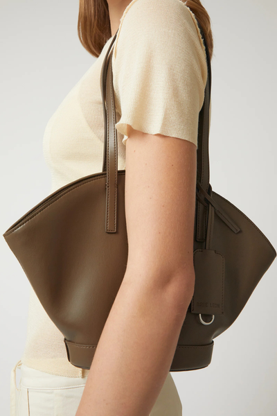 Close-up side view of the forest green Brie Leon Heather Mini Tote worn on the shoulder, highlighting its sculptural winged design and fine shoulder straps.