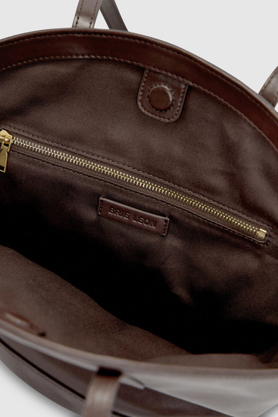 Interior shot of the open dark brown Brie Leon Heather Mini Tote, featuring a tonal cotton twill lining, hidden magnetic closure, gold zip pocket hardware, and debossed leather logo patch.