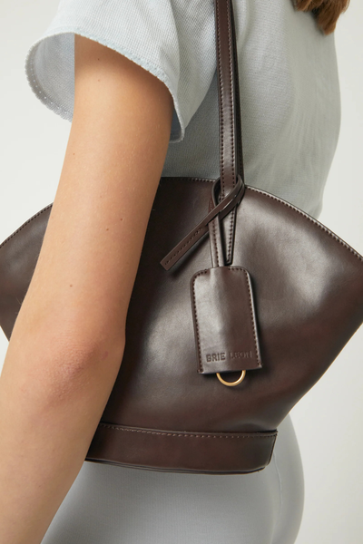 Close-up over-the-shoulder view of the dark brown Brie Leon Heather Mini Tote in recycled corn leather, highlighting its smooth finish, gold hardware loop on the key charm, and fine stitching.