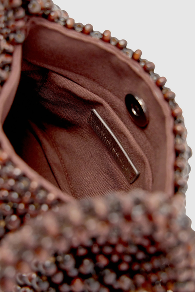 Close-up interior view of the mini bag showcasing the dark brown lining, magnetic snap closure, internal patch pocket, and metallic branding tag.