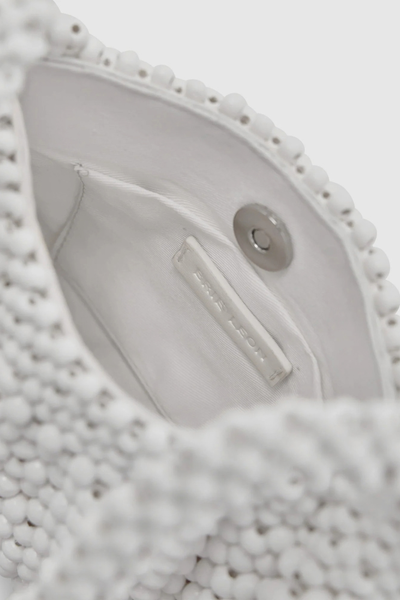 Close-up interior view of the oat mini bag showing the white textile lining, magnetic snap closure, internal patch pocket, and "Brie Leon" branded metal tab.