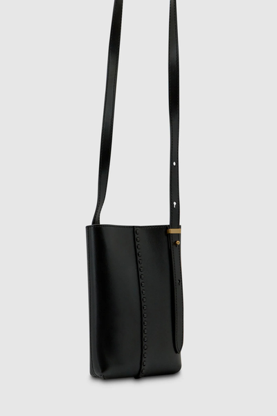 Three-quarter angle studio view of the Brie Leon Reese Pocket Bag in black featuring oversized central hand-stitching and an adjustable thin shoulder strap with gold hardware.