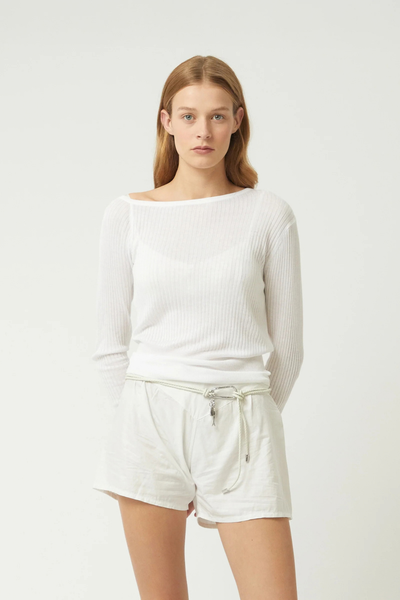 Studio front view of a model wearing a white long-sleeve knit top and white shorts styled with the elderflower-colored braided recycled leather Scout knot belt featuring a silver carabiner and charms.