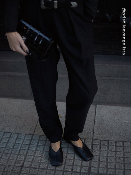 Low-angle shot on a paved sidewalk showing black Senso Brynn calf leather high-cut flats with square toe and center seam detailing, paired with black tailored trousers.