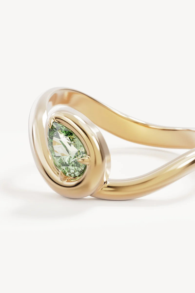 Close-up product shot of the By Charlotte Embrace Growth Ring in 18k Gold Vermeil, showcasing the pear-cut lab-grown green tourmaline set in a organic bypass band.