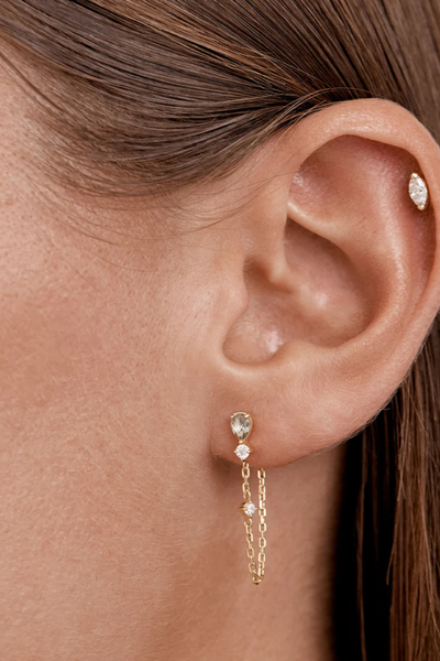 On-model lifestyle view showing the By Charlotte Aura Chain Earring in 18k Gold Plated worn in an earlobe piercing with the chain looped underneath.