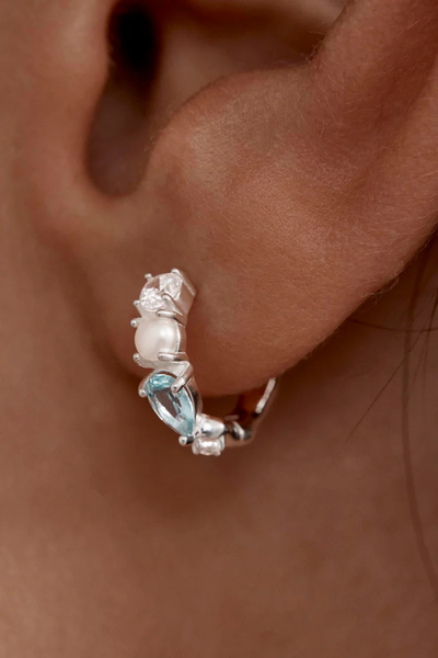 A high-resolution profile lifestyle photograph featuring a model wearing the sterling silver and gemstone huggie hoop earring in a first lobe piercing, effectively illustrating its 3.5mm hoop width, scale, and secure, comfortable fit on the earlobe.