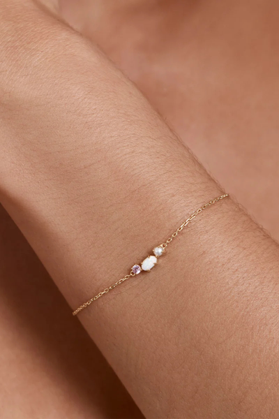 On-model lifestyle view of the By Charlotte Cosmic Bloom Bracelet in 18k Gold Vermeil worn on a wrist, highlighting the multi-stone centerpiece set on a fine gold chain.