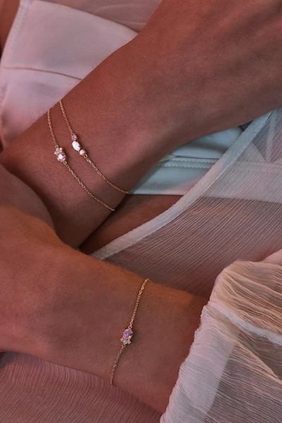 On-model lifestyle view showcasing the By Charlotte Cosmic Bloom Bracelet in 18k Gold Vermeil stacked alongside the matching Embrace Love Bracelet.
