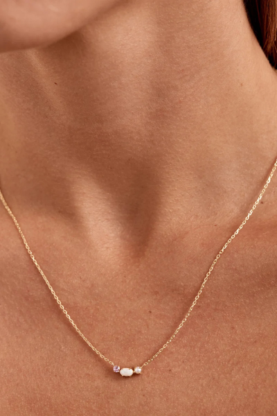 Close-up lifestyle view of a model wearing the By Charlotte Cosmic Bloom Necklace in 18k Gold Vermeil, showcasing the delicate gemstone pendant against the collarbone.