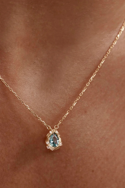 A mid-length lifestyle campaign portrait on a model demonstrating the full drape and scale of the fine gold chain, highlighting its adjustable 18-inch length and oceanic theme.