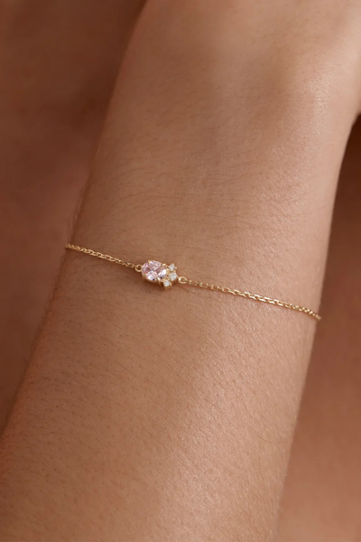 On-model lifestyle view of the By Charlotte Embrace Love Bracelet in 18k Gold Vermeil worn on a wrist, displaying the fine gold chain and delicate pink gemstone centerpiece.