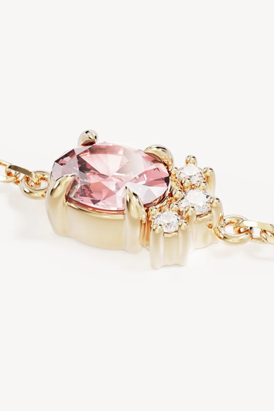 Extreme macro close-up product view detailing the prong-set oval pink cubic zirconia accented by small round white cubic zirconias on the By Charlotte Embrace Love Bracelet in 18k Gold Vermeil.