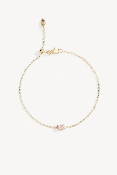 Studio product shot of the By Charlotte Embrace Love Bracelet in 18k Gold Vermeil laid flat against a white background, featuring a delicate diamond-cut cable chain centered with an oval-cut pink cubic zirconia and clear accent stones, complete with an adjustable silicone slider and lobster clasp.
