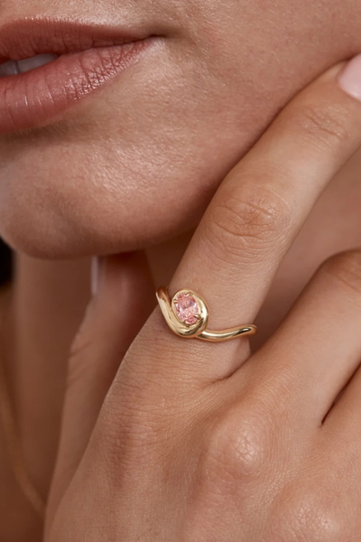 Macro close-up shot of the By Charlotte Embrace Love Ring in 18k Gold Vermeil, highlighting the faceted 6 x 4mm pink oval cubic zirconia and smooth polished gold finish.