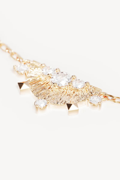 A macro close-up studio shot highlighting the intricate design of the fan-shaped 18k gold vermeil pendant, showcasing its distinct textured finish, radiating etched lines, multi-sized prong-set cubic zirconias, and sharp geometric stud details along the outer edge.