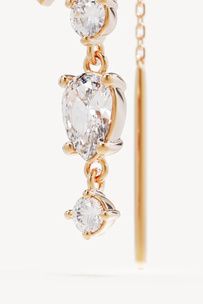 A three-quarter studio product shot of a pair of 18k Gold Vermeil Lotus Rain Thread Earrings standing upright against a clean white background, showcasing the curved ear hooks, the textured fan-shaped lotus motifs, and the multi-tiered drop design encrusted with baguette, round, and pear-cut cubic zirconias.