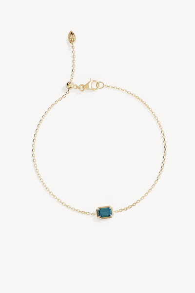 Studio product shot of the By Charlotte Trust Your Intuition Bracelet in 18k Gold Vermeil laid flat against a white background, featuring a fine diamond-cut cable chain centered with an emerald-cut deep green nano tourmaline Paraiba pendant, adjustable silicone ball slider, and lobster clasp closure.