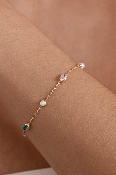 On-model lifestyle view demonstrating the By Charlotte You Are Infinite Bracelet in 18k Gold Plated worn on a wrist, displaying the array of colorful gemstone station charms.