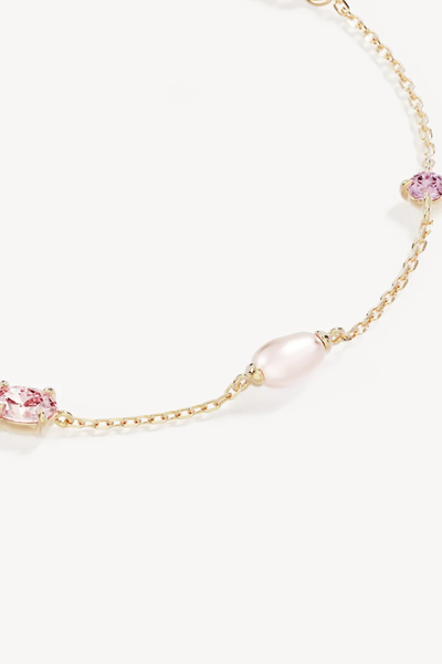 Macro close-up product view highlighting the delicate gold chain setting of a freshwater pearl and claw-set pink cubic zirconia on the By Charlotte You Are Infinite Bracelet in 18k Gold Plated.