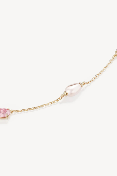 Macro close-up shot of the By Charlotte You Are Infinite Choker in 18k Gold Plated, highlighting a freshwater pearl charm and a claw-set pink cubic zirconia stone.