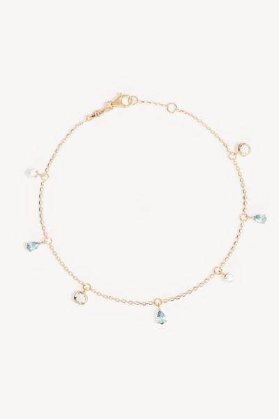 A flat lay studio product shot of the 18k Gold Vermeil Breathe In Stillness Anklet arranged in a circle against a clean white background, showcasing its lobster clasp, delicate chain link, and alternating charm drops of freshwater pearls, round bezel-set cubic zirconias, and teardrop-cut mint green tourmaline nano gemstones.