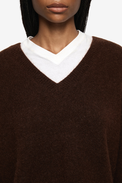 Detailed shot of the wide V-neckline and dropped shoulder seams, showcasing the soft drape of the dark brown mohair fabrication.
