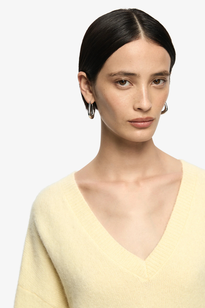 Detailed shot of the wide V-neck and dropped shoulder seams, showcasing the jumper's effortless and elevated winter aesthetic.
