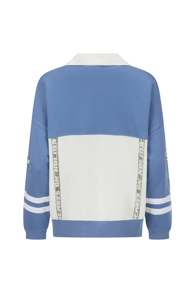 A full back view on a model, illustrating the continuous color-blocked design line wrapping around the torso and sleeves, anchored by a thick, cream-colored ribbed hem.