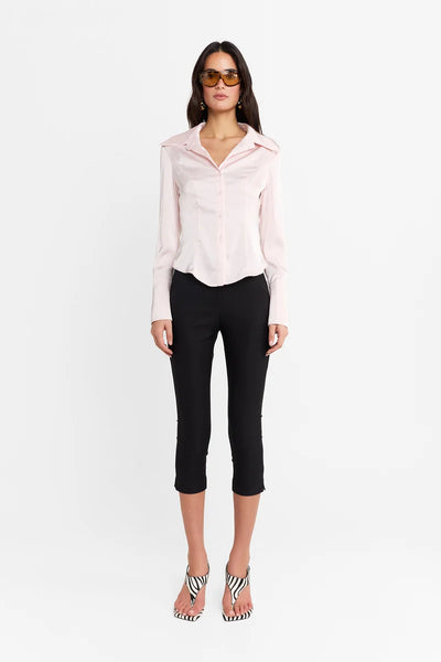 Straight-on front view of a model wearing the black capris with a pink satin blouse and zebra-print heels against a plain white background.