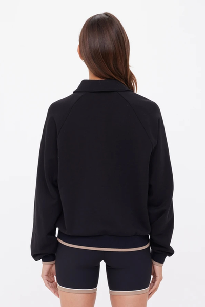 A full back view of the black Elle Polo, illustrating the 60cm length (size S) and the clean, seamless finish of the French terry fabrication.
