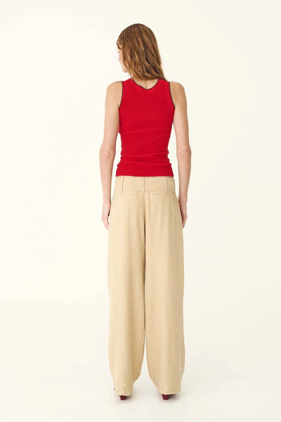Full-length studio rear view of a model wearing the ROWIE Carlotta Linen Curve Pants in Khaki styled with a fitted red tank top, highlighting the back welt pocket details, mid-rise fit, and fluid linen-blend drape.