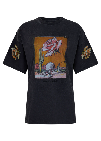 Front flat lay product shot of the Kinga Csilla Desert Rose OG Tee in stonewashed black cotton jersey, showcasing the central skull, cactus, and rose artwork alongside printed sleeve details.