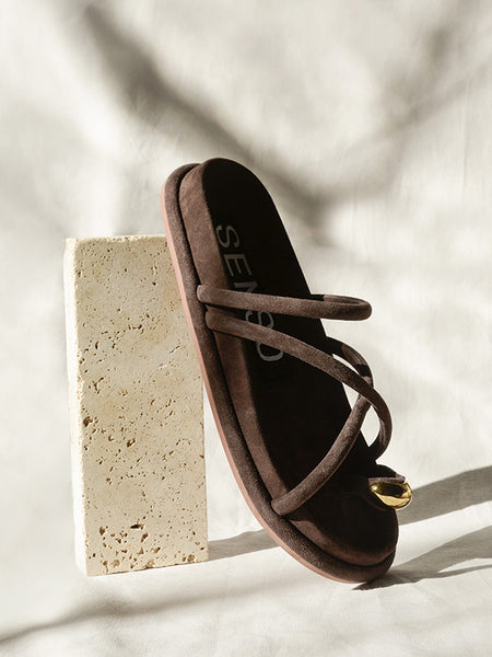 A clean, angled hero profile studio shot of the Senso Domenica slip-on sandal in Cocoa brown, showcasing the soft matte texture of the suede crossover straps and the minimal, flat sole design.