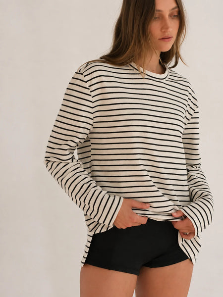 Half-body studio portrait highlighting the side seam split detail and relaxed fit of the Zulu & Zephyr Jersey Long Sleeve Top in Black Stripe over black active shorts.