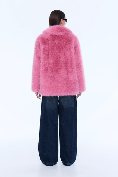 A full-length profile shot showcasing the side view of the model wearing the bright pink jacket. This perspective highlights the relaxed drop-shoulder construction, the substantial volume of the oversized silhouette, and the long sleeves extending past the hips.